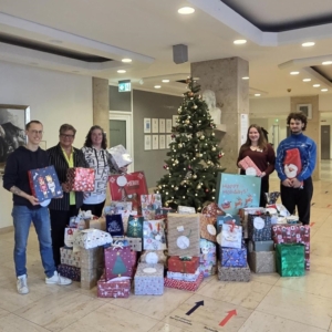 Die Organisatorinnen des Luisenhospitals übergeben vor dem Wunschbaum die vielen Geschenke an Mitarbeitende der Suchthilfe Aachen.