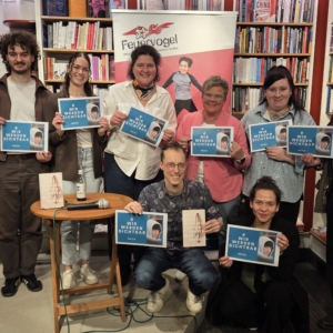 Die Veranstalter und die Autorin (7 Personen) halten ein Plakat mit dem Motto "Wir werden sichtbar" hoch.