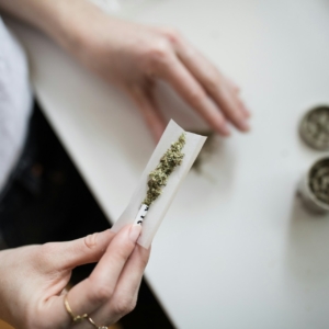 Auf dem Bild sieht man die Hände einer weiblichen Person, die einen Joint herstellt.