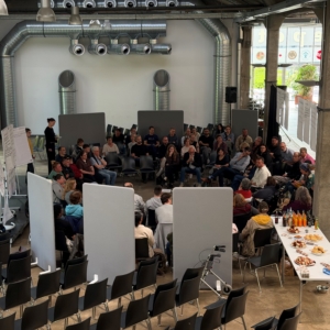 Die Gäste der Veranstaltung - darunter wohnungslose Menschen, Politiker und Interessierte, sitzen in einem mehrreihigen Kreis und diskutieren.