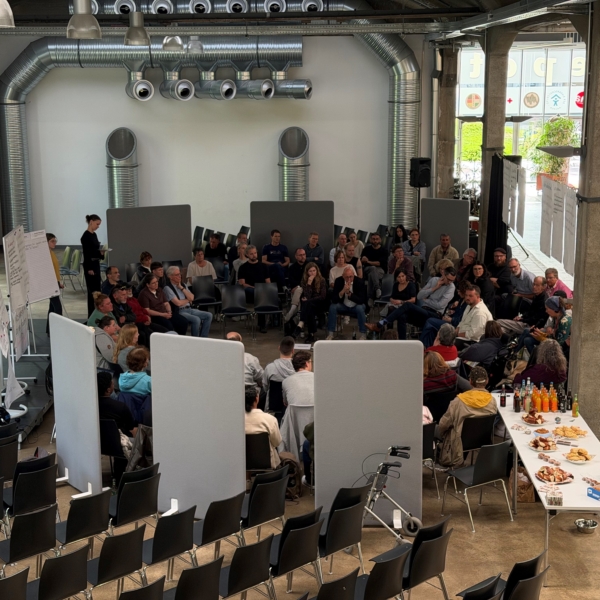 Die Gäste der Veranstaltung - darunter wohnungslose Menschen, Politiker und Interessierte, sitzen in einem mehrreihigen Kreis und diskutieren.